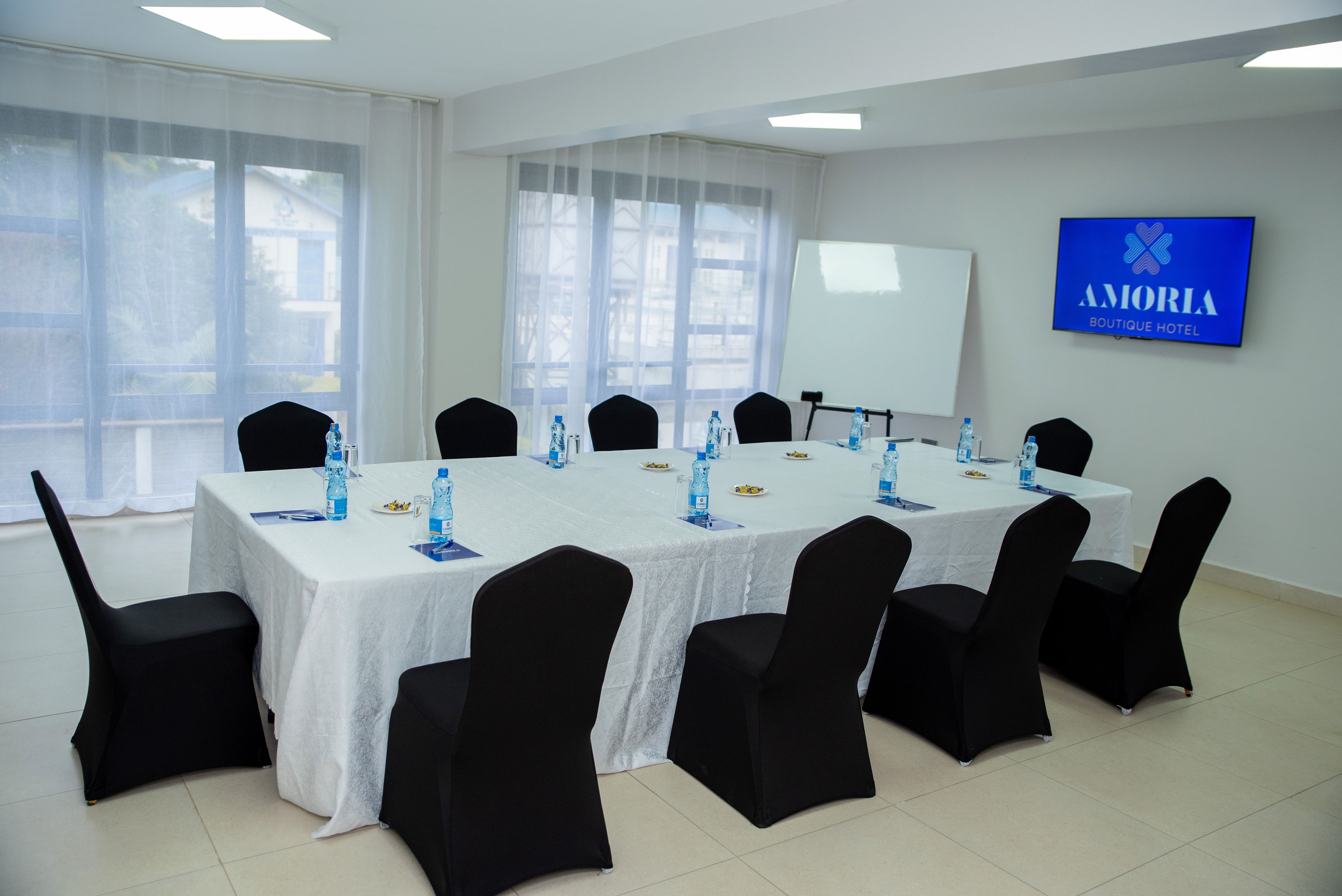 The conference room facing the Amoria screen, with white table linen and black covered chairs