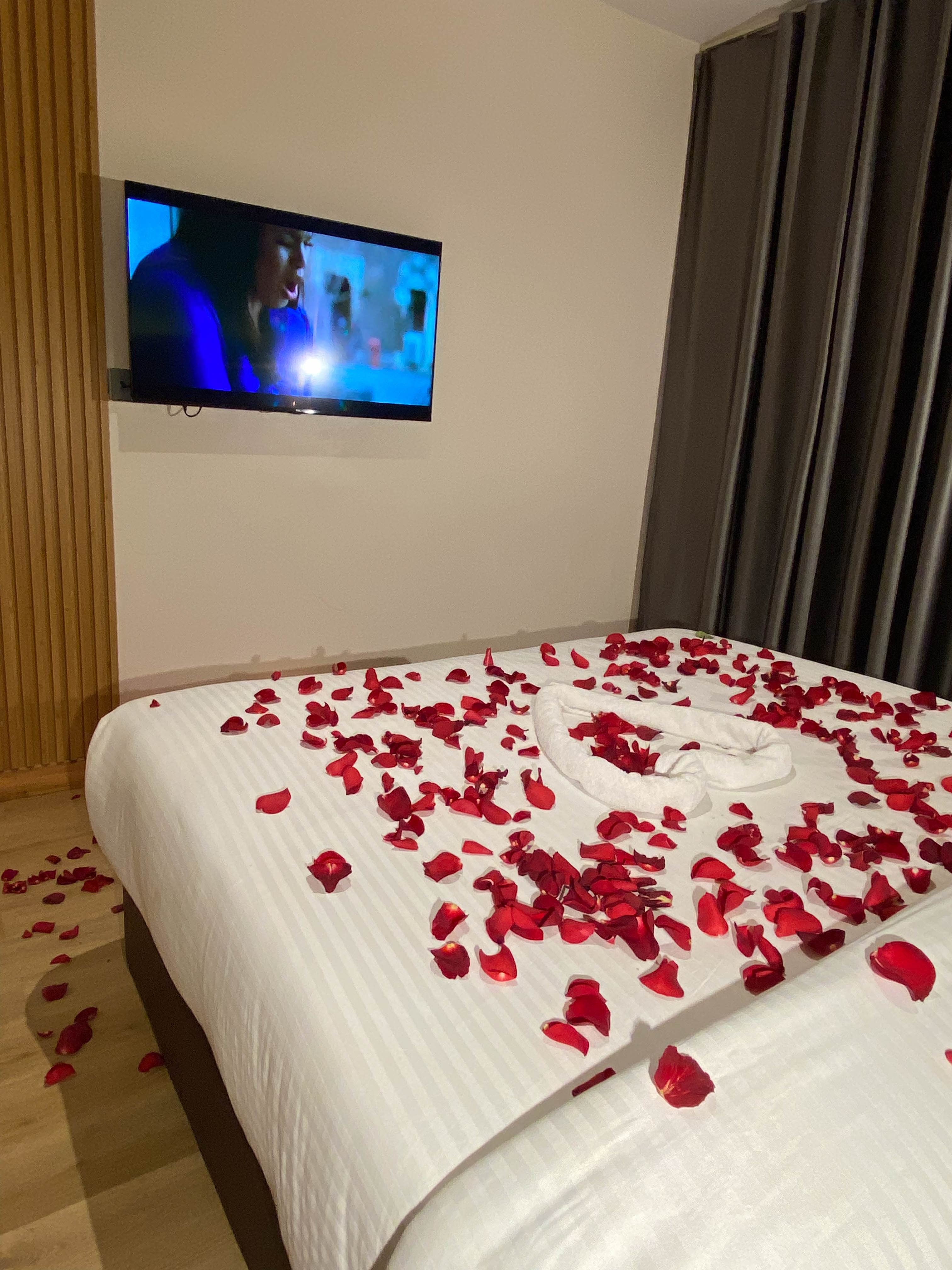 Petal-filled towel heart on a bed, rose petals trailing to the floor