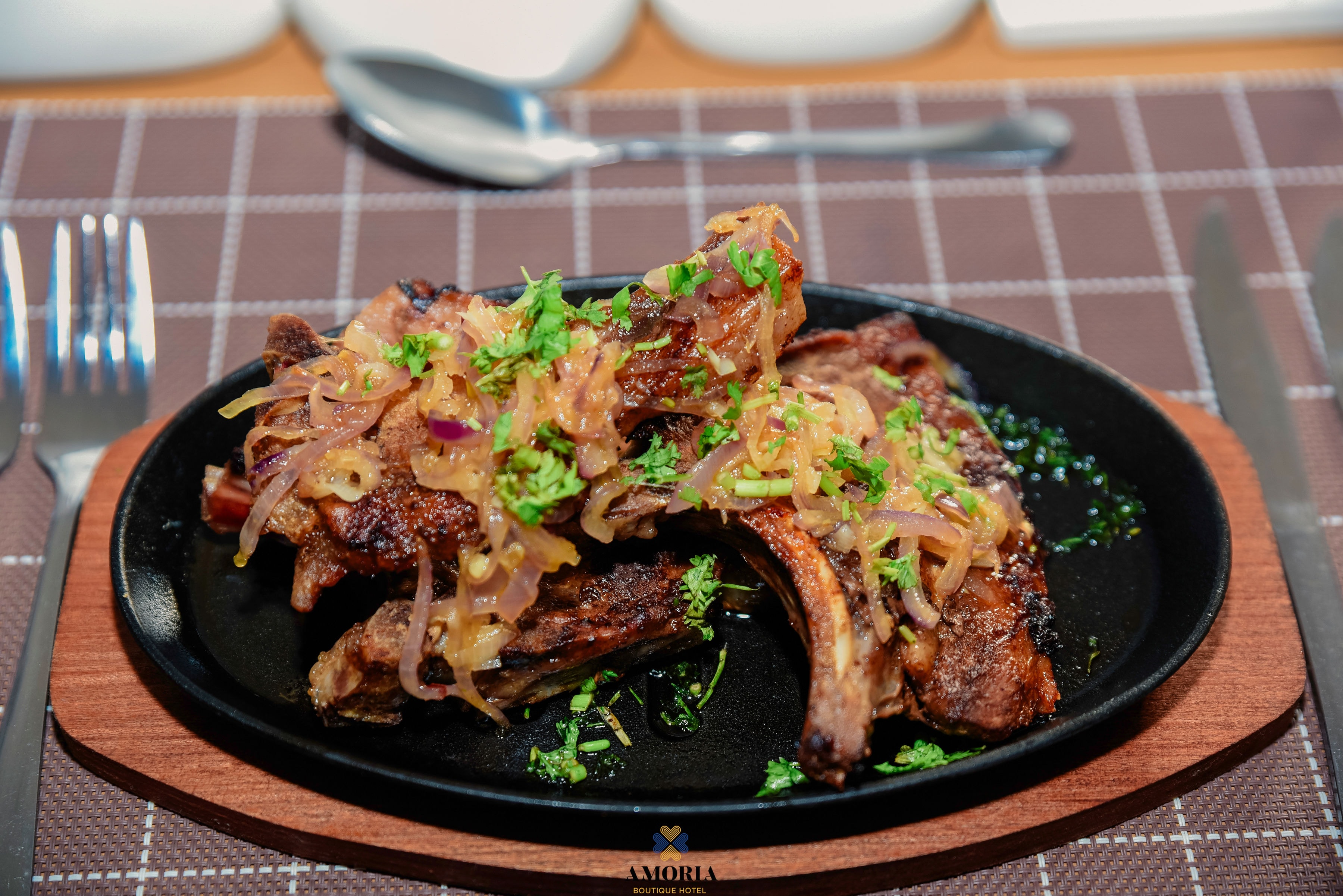 Sizzling glazed ribs with herbs served on a black hotplate