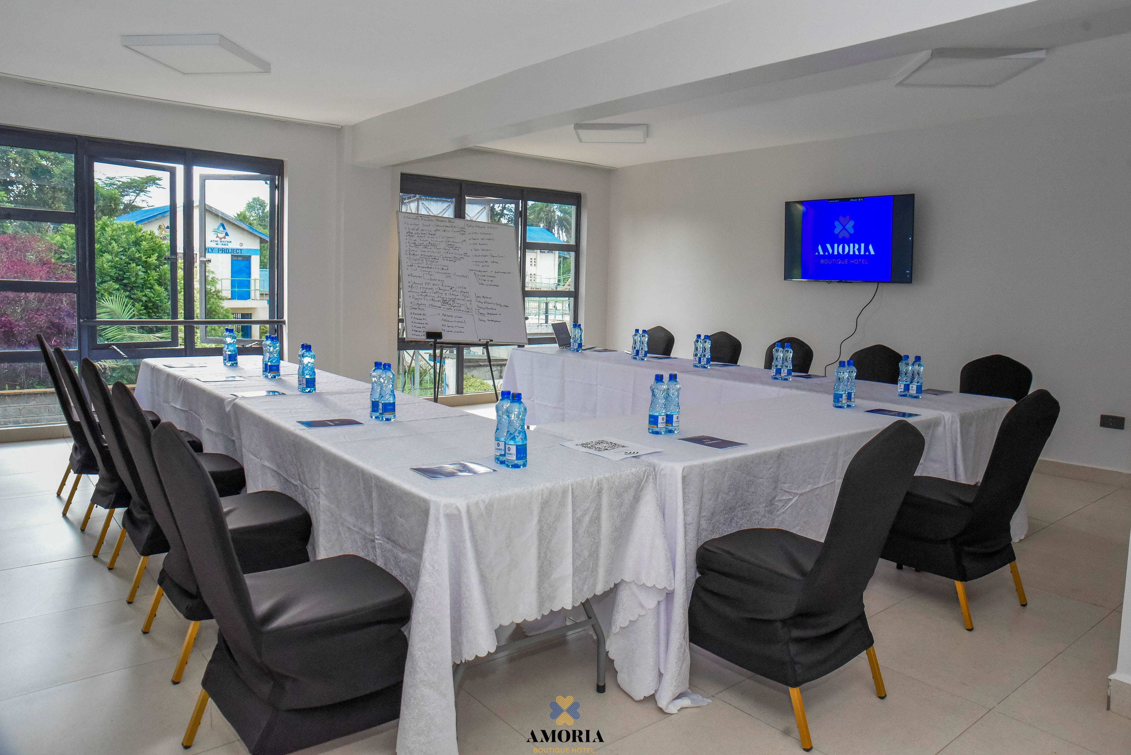 The conference hall in white linen, set U-shape with branded water at every seat and Amoria on the wall screen