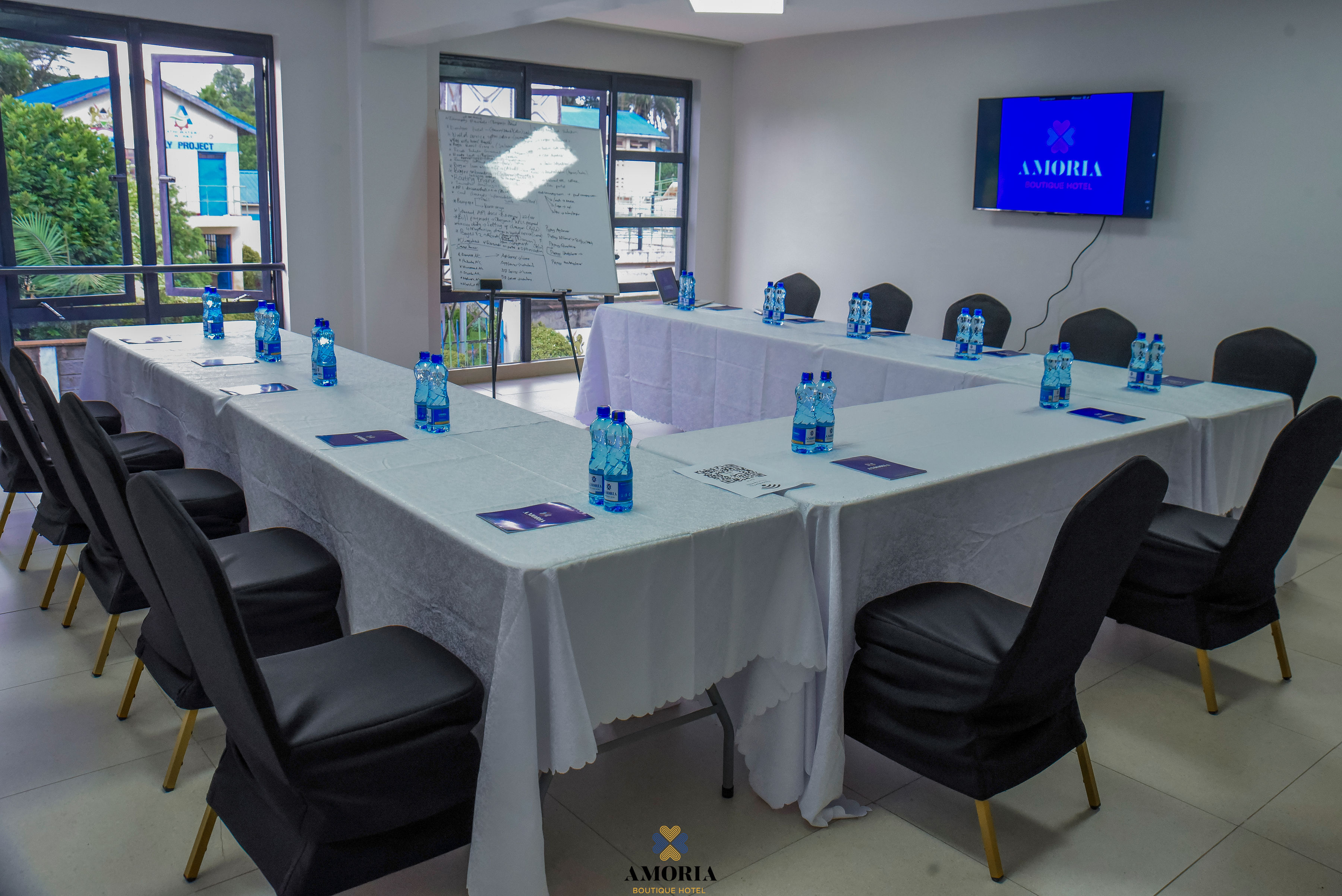 U-shaped conference setup at Amoria with white tablecloths, water bottles and natural window light