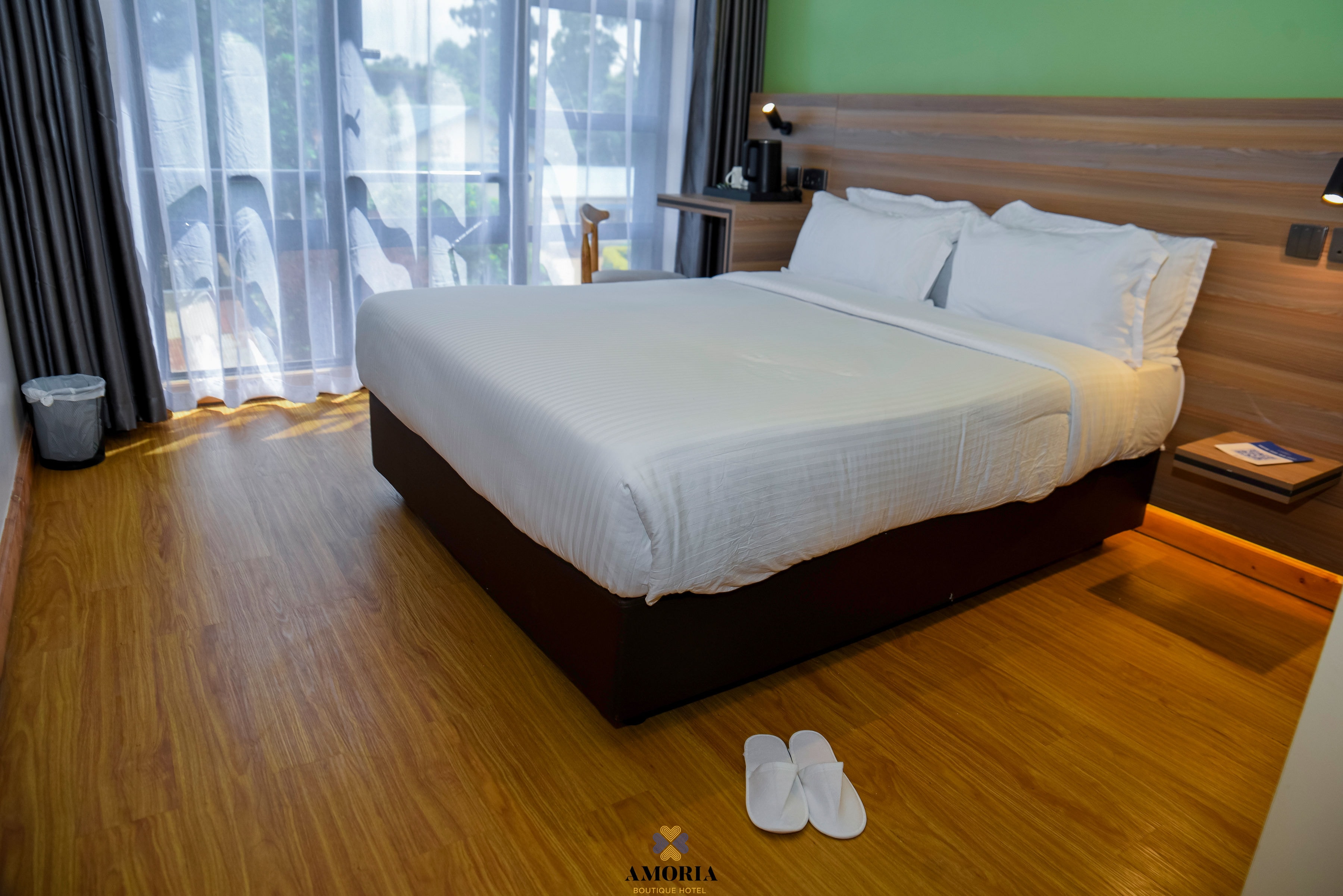 Guest room at Amoria with a white king bed, wood floors and morning light through sheer curtains