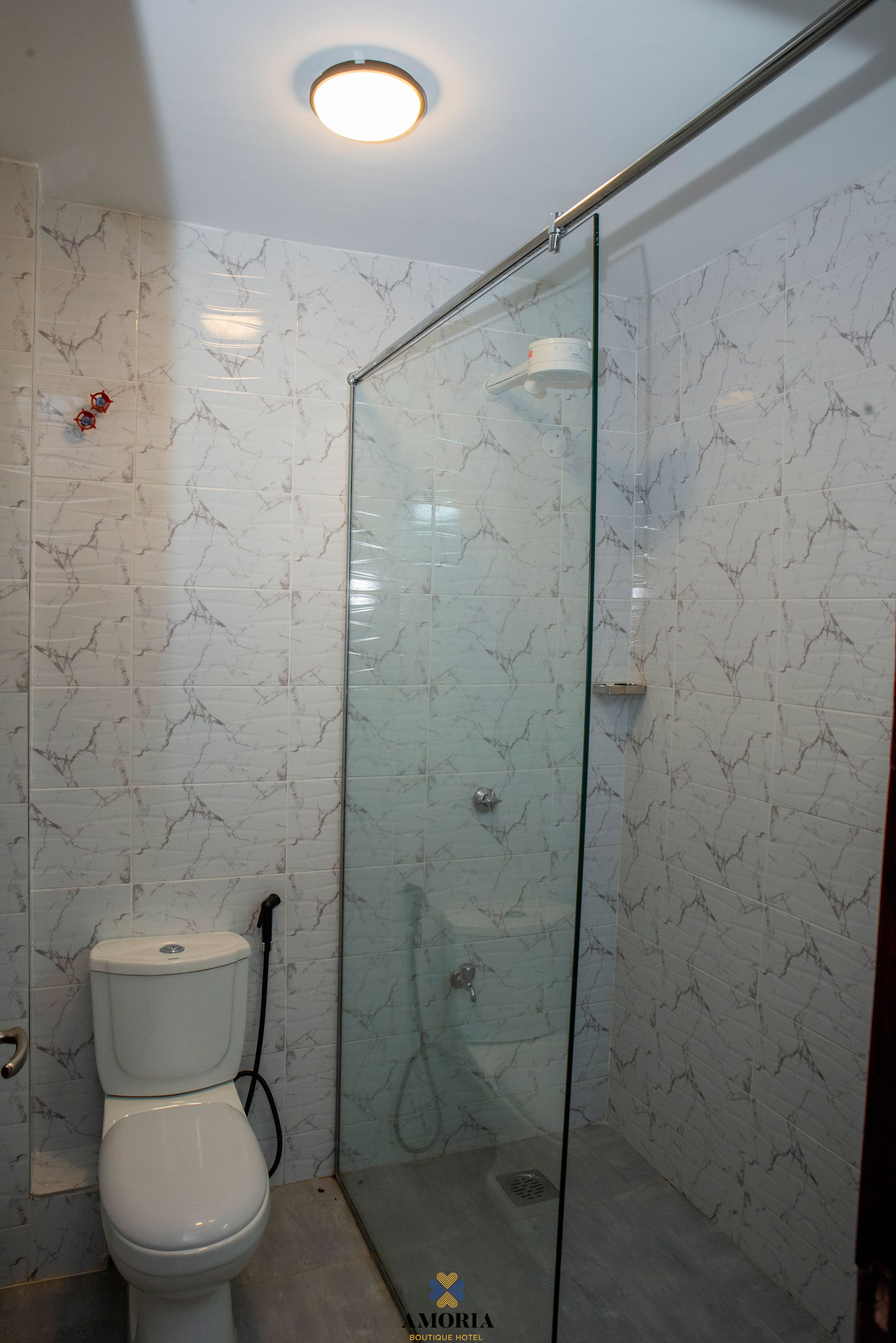 Glass rain shower with marble-patterned tiles