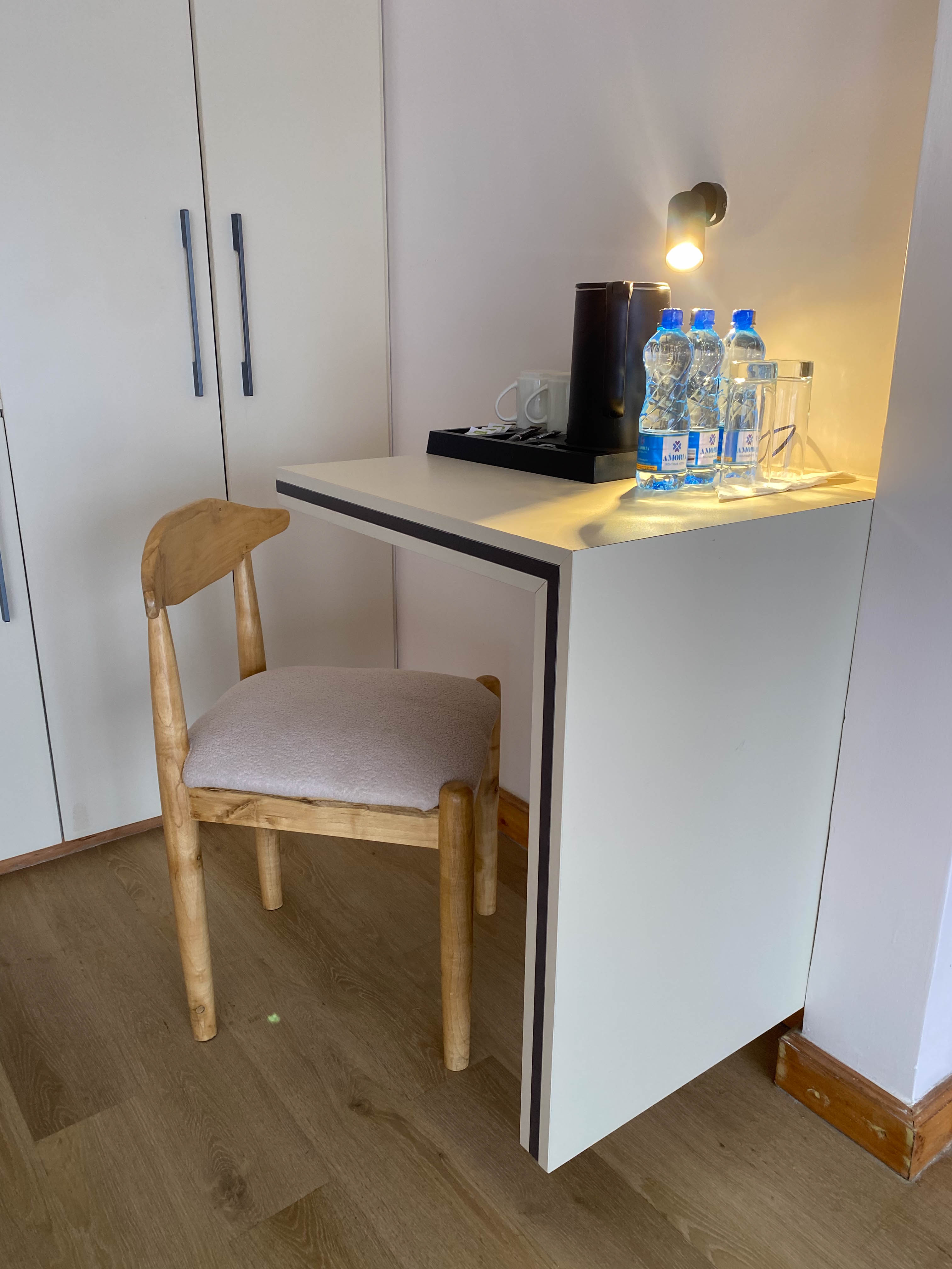 The Executive room's desk nook — sculpted wooden chair, kettle tray and Amoria-branded water under warm light