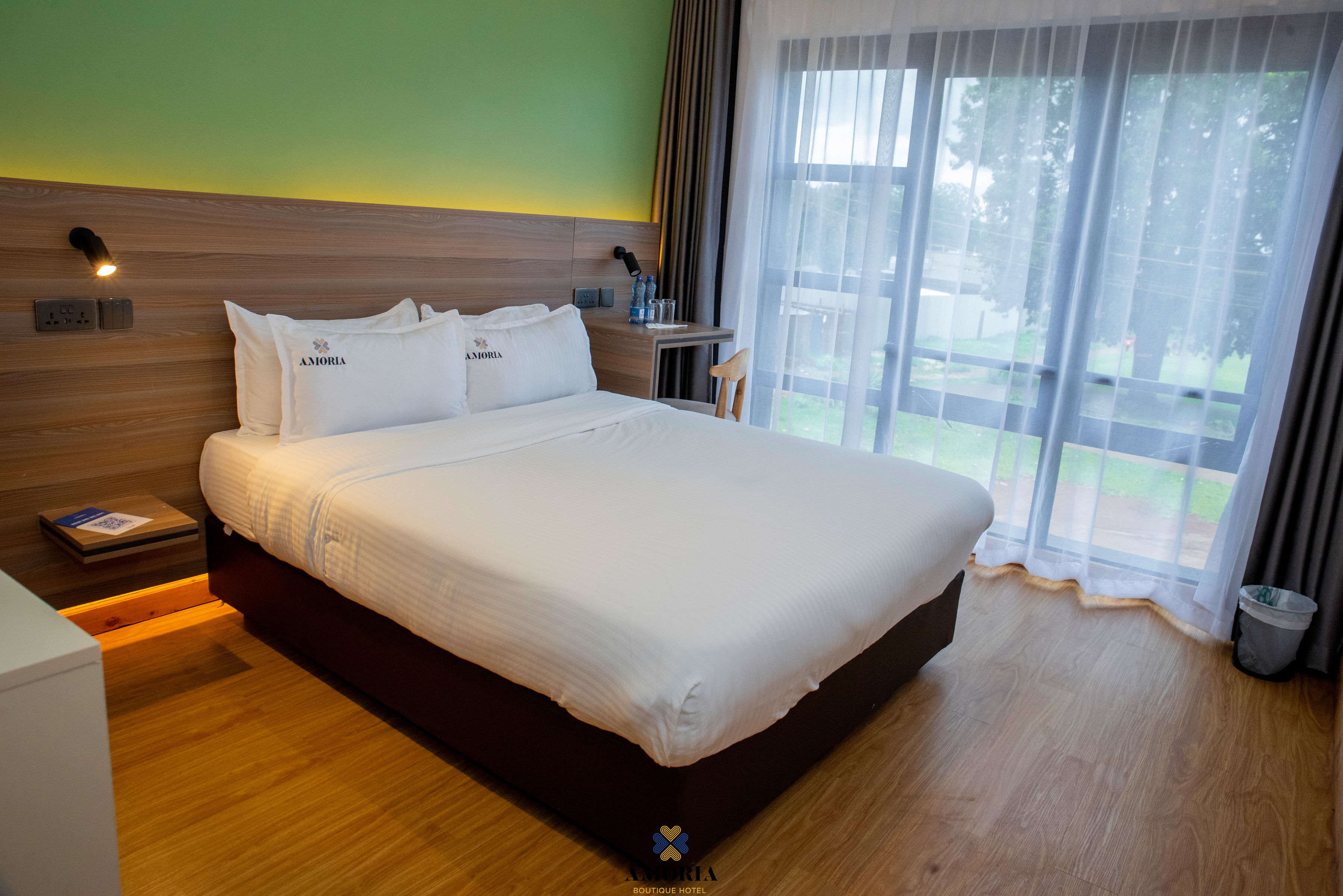 Guest room with a white king bed and a floor-to-ceiling window