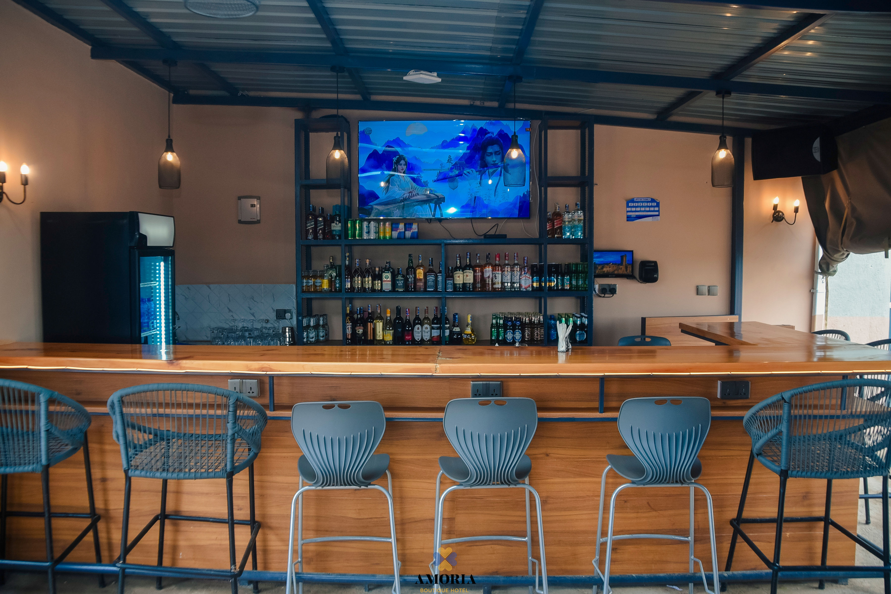 The Amoria bar with blue stools, backlit shelves and a wide TV