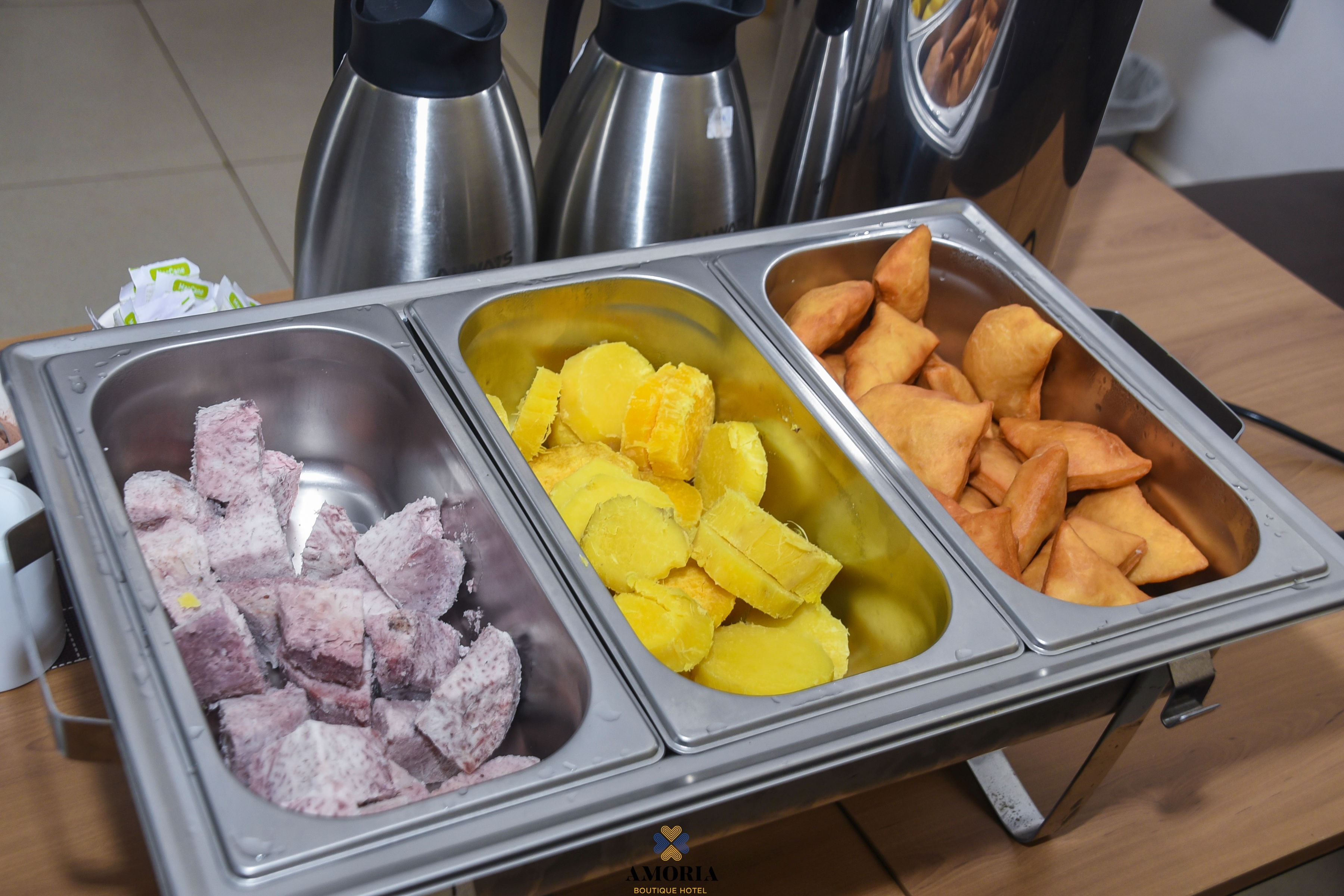 Buffet trays of samosas, sweet potato and arrowroot beside coffee flasks