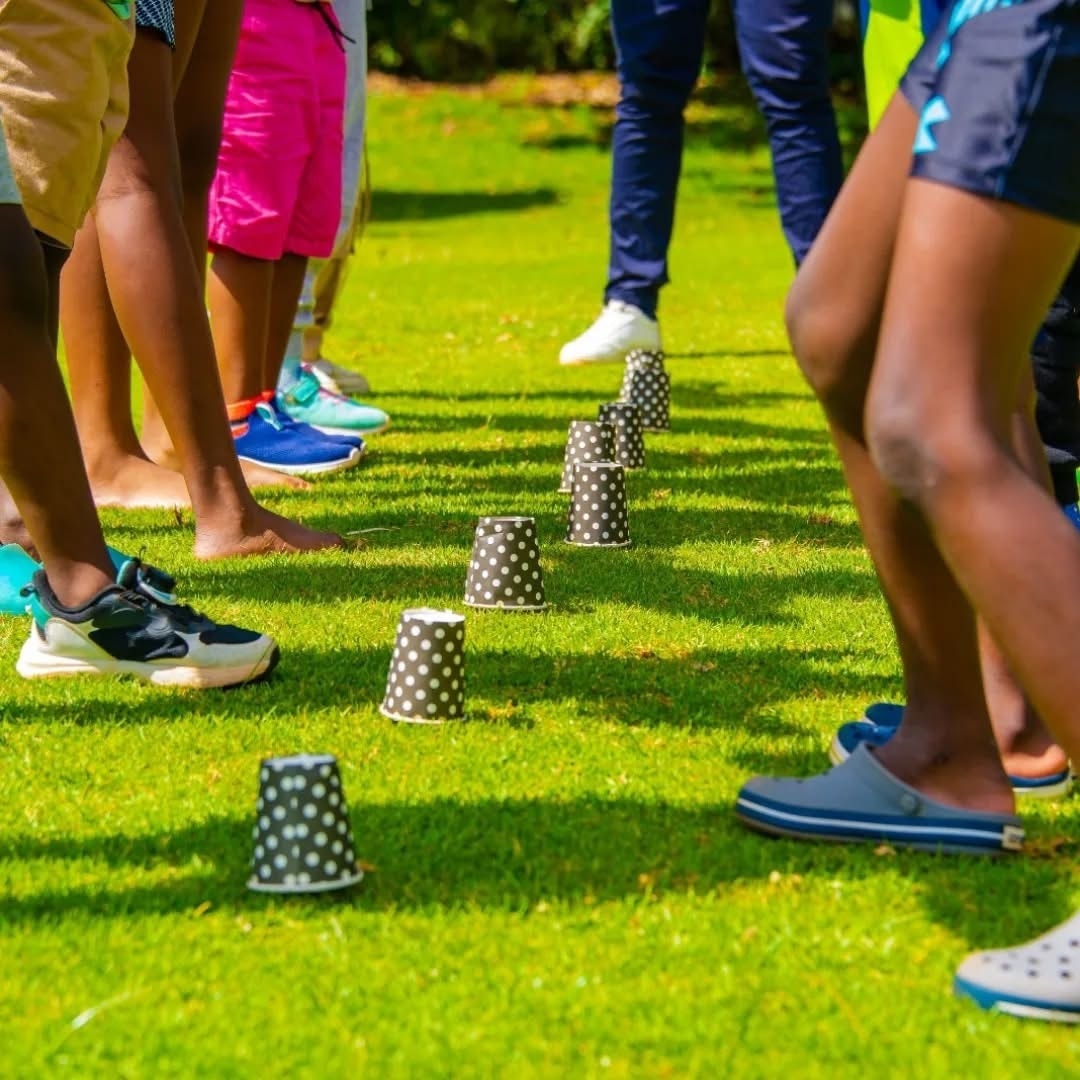 Children's feet mid-game on the lawn, dotted paper cups scattered across the grass