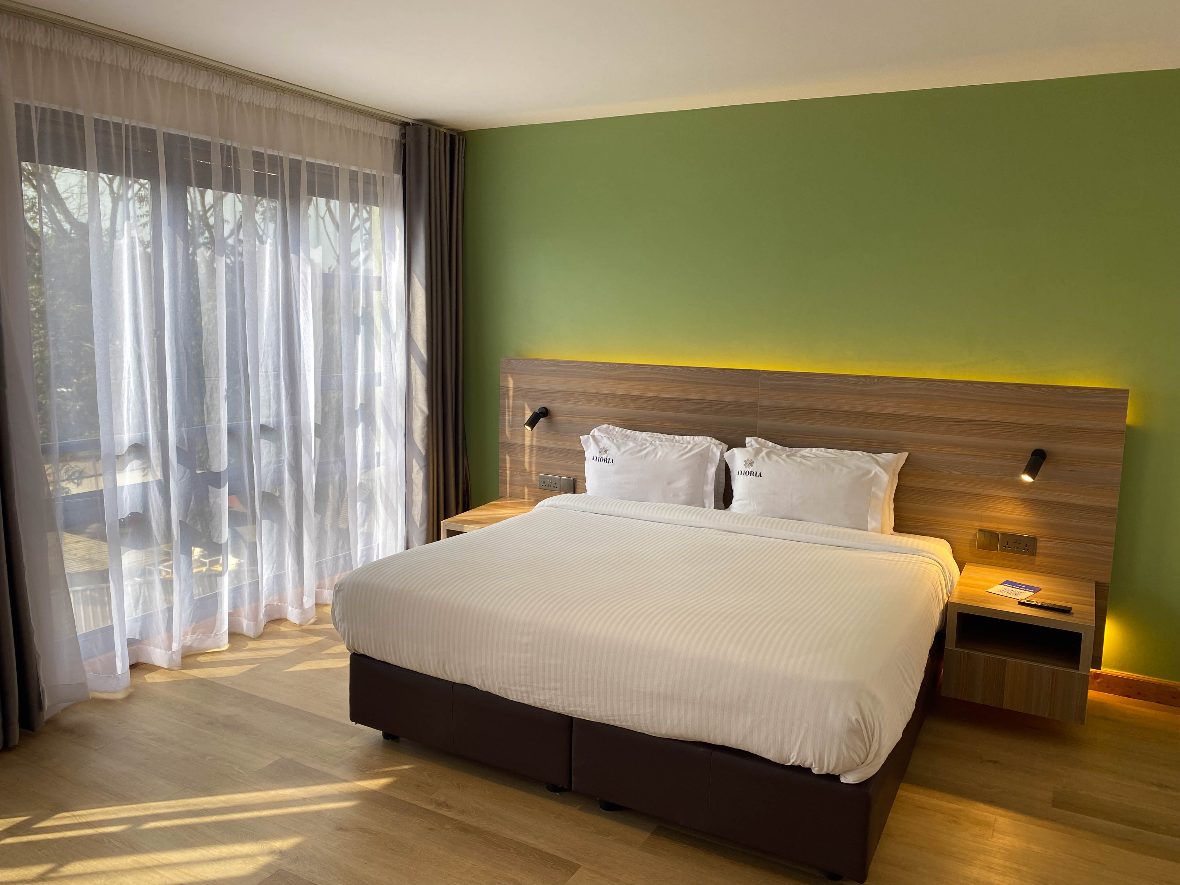 The Executive room from the corner — king bed, backlit headboard and balcony doors